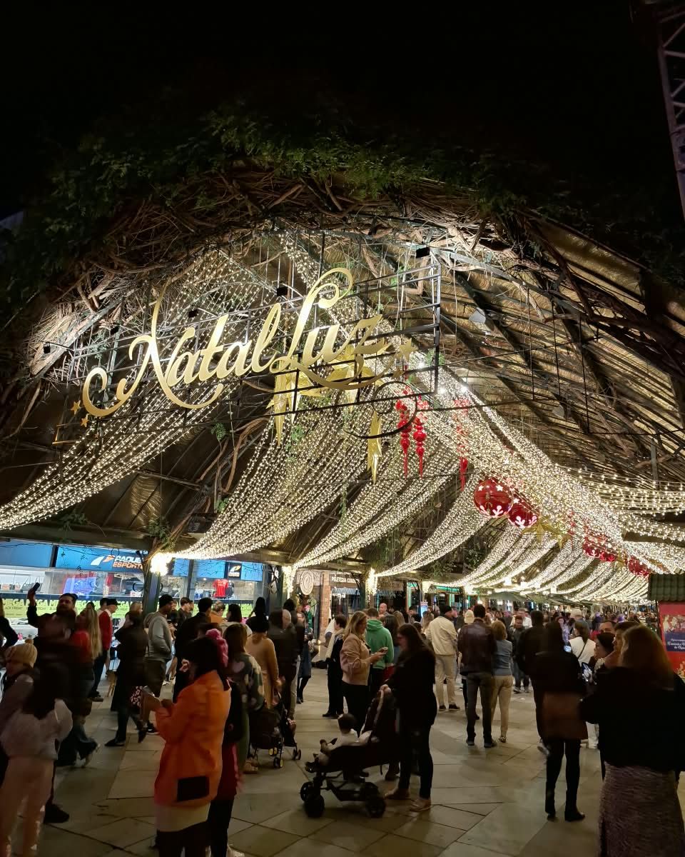 Rua Coberta de Gramado decorada com cortinas de luzes e o letreiro do Natal Luz, cheia de visitantes à noite