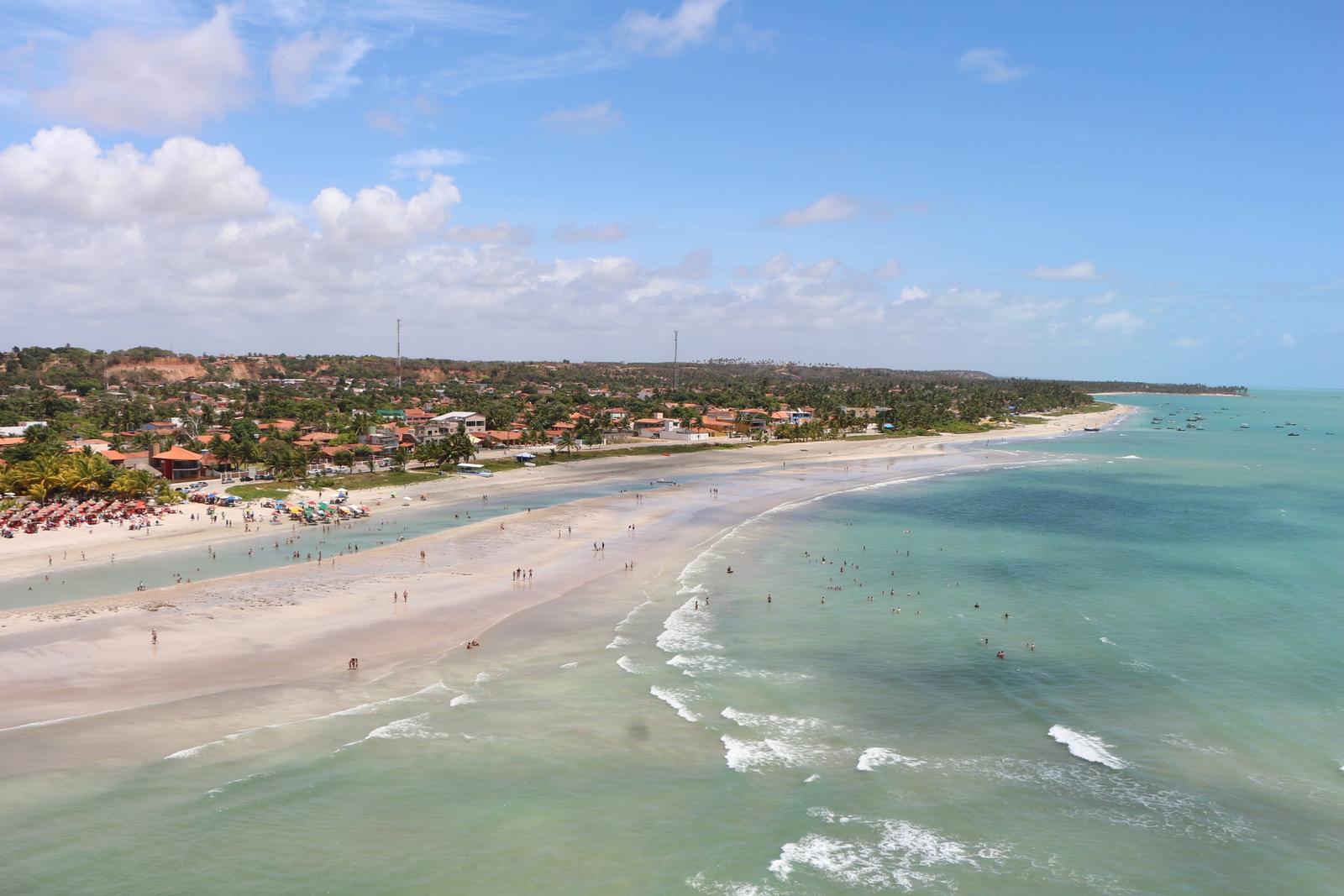 Vista do alto da praia de Paripueira, no litoral norte de Alagoas, com areia clara e mar esverdeado